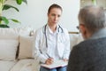 Female doctor examining older senior man in doctor office or at home. Old man patient and doctor have consultation in Royalty Free Stock Photo