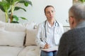 Female doctor examining older senior man in doctor office or at home. Old man patient and doctor have consultation in Royalty Free Stock Photo