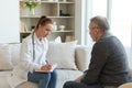 Female doctor examining older senior man in doctor office or at home. Old man patient and doctor have consultation in Royalty Free Stock Photo