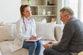 Female doctor examining older senior man in doctor office or at home. Old man patient and doctor have consultation in Royalty Free Stock Photo