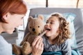 Female doctor examining small girl in bed in hospital. Royalty Free Stock Photo