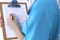 Female doctor filling up medical form on clipboard closeup. Physician finish up examining his patient in hospital an Royalty Free Stock Photo