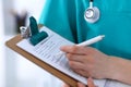 Female doctor filling up medical form on clipboard closeup. Physician finish up examining his patient in hospital an Royalty Free Stock Photo