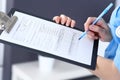 Female doctor filling up medical form on clipboard, closeup. Physician finishing up examining his patient in hospita Royalty Free Stock Photo