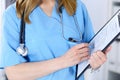 Female doctor filling up medical form on clipboard, closeup. Physician finishing up examining his patient in hospita Royalty Free Stock Photo