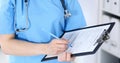 Female doctor filling up medical form on clipboard, closeup. Physician finishing up examining his patient in hospita Royalty Free Stock Photo