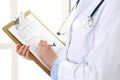 Female doctor filling up medical form on clipboard closeup. Physician finishing up examining his patient in hospital an Royalty Free Stock Photo