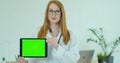 Female Doctor in glasses demonstrating digital tablet with chroma key in hospital, Portrait of woman in white gown with Royalty Free Stock Photo