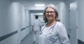 Female doctor in glasses stands in clinic corridor, looks at camera Royalty Free Stock Photo