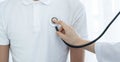 Female doctor hand examining the health of male patients chest with a stethoscope Royalty Free Stock Photo