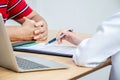 Female doctor hand hold silver pen filling patient history list at clipboard pad, Patient listening receiving in medical clinic