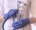 Female doctor hands closeup, holding metal modern stethoscope in hands. Physician with hospital tool and blue latex Royalty Free Stock Photo