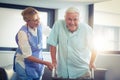 Female doctor helping senior man to walk with walker