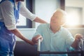 Female doctor helping senior man to walk with walker