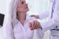 Female doctor helps sick mature woman stand up in office