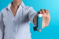 Female doctor holding asthma inhaler on color background, closeup. Royalty Free Stock Photo