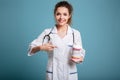 Female doctor holding bottle of pills and pointing at her Royalty Free Stock Photo