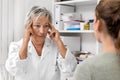 Female doctor holding her temporal, demonstration of headache or neuralgia pain