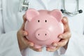 Female Doctor Holding Piggy Bank. Royalty Free Stock Photo