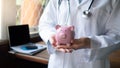 Female doctor is holding piggy bank, saving protection concept Royalty Free Stock Photo