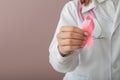 Female doctor holding pink ribbon on color background, closeup. Breast cancer awareness concept Royalty Free Stock Photo