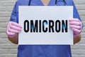 A female doctor holds a sheet of paper with the text of the new variant covid virus Omicron. Hands of a nurse in protective Royalty Free Stock Photo