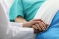 Female doctor holds sick man hospital bed by hand Royalty Free Stock Photo