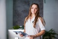 Female doctor with lab coat in her office holding a clipboard