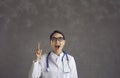 Female doctor in lab coat looking up pointing with raised forefinger idea Royalty Free Stock Photo