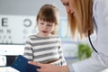 Female doctor listening cute little patient and writing registration information on clipboard pad Royalty Free Stock Photo