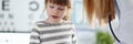 Female doctor listening cute little patient and writing registration information on clipboard pad Royalty Free Stock Photo