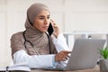 Female doctor looking at laptop screen and talking on phone Royalty Free Stock Photo