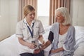 Female Doctor Making Home Visit To Senior Woman In Bedroom For Blood Pressure Check Royalty Free Stock Photo