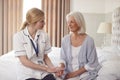 Female Doctor Making Home Visit To Senior Woman For Medical Check Offering Reassurance