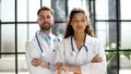 a female doctor and a male doctor are standing in the office with their arms crossed Royalty Free Stock Photo