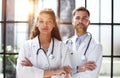 a female doctor and a male doctor are standing in the office with their arms crossed Royalty Free Stock Photo