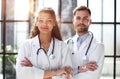 a female doctor and a male doctor are standing in the office with their arms crossed Royalty Free Stock Photo