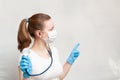 Female doctor in mask pointing with finger on background