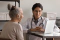 Female doctor and mature patient use laptop at consultation Royalty Free Stock Photo