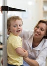 Female doctor measuring height of little boy in clinic