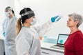 Female doctor measuring senior patient temperature for coronavirus disease - Focus on right woman