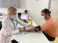 Female doctor in medical facemask measure blood pressure with electronic monitor in hospital. Royalty Free Stock Photo