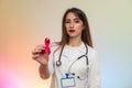 Female doctor in medical uniform holding red ribbon. AIDS day concept