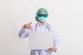 Female doctor in medical uniform and mask holding blank white banner Royalty Free Stock Photo