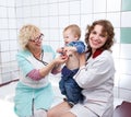 Female doctor and nurse examine little angry baby