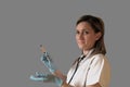 Female doctor or nurse holds in hand a syringe with medicine. Woman looks at camera, wears uniform, blue latex gloves and Royalty Free Stock Photo