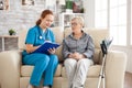 Female doctor in nursing home doing survey on senior woman