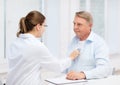 Female doctor with old man listening to heart beat