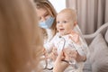 Female doctor pediatrician examining smiling baby girl with stethoscope doing a month checkup, checks heart and lungs Royalty Free Stock Photo