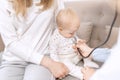 Female doctor pediatrician examining smiling baby girl with stethoscope doing a month checkup, checks heart and lungs Royalty Free Stock Photo